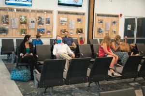 Airport waiting area with families and people sitting.